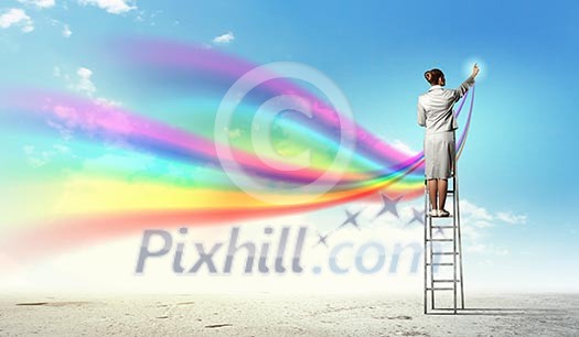 Young woman standing on ladder drawing splashes with finger Young woman standing on ladder drawing splashes with finger