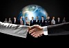 business handshake against black background and standing businesspeople