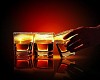 Hand holding one of three glasses of whiskey with sea illustration in