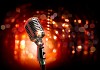 Single retro microphone against colourful background with lights