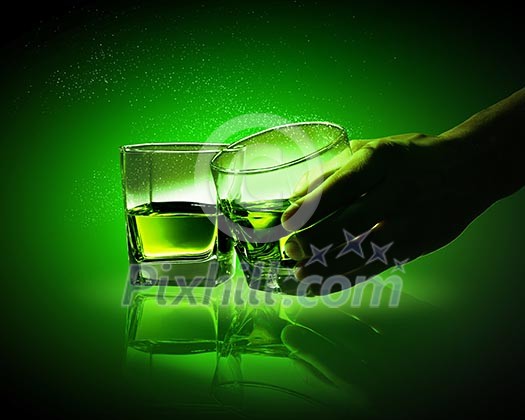 Hand holding one of two glasses of green absinth Hand holding one of two glasses of green absinth