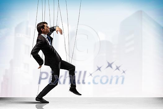 Image of businessman hanging on strings like marionette against city background. Conceptual photography Image of businessman hanging on strings like marionette against city background. Conceptual photography