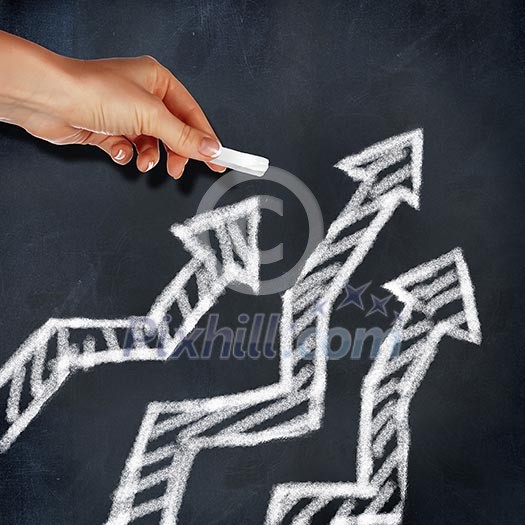 School blackboard and hand with chalk drawing arrows on it