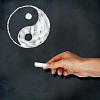 School blackboard and hand with chalk drawing yin-yang symbol