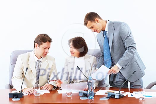 Image of three businesspeople sitting at table at conference Image of three businesspeople sitting at table at conference