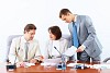 Image of three businesspeople sitting at table at conference