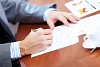 Image of businessman's hands signing documents at meeting