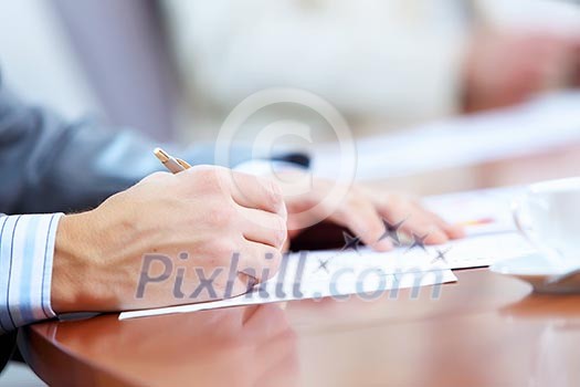 Image of businessman's hands signing documents at meeting