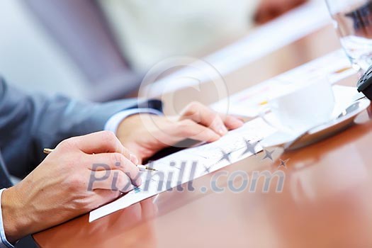 Image of businessman's hands signing documents at meeting