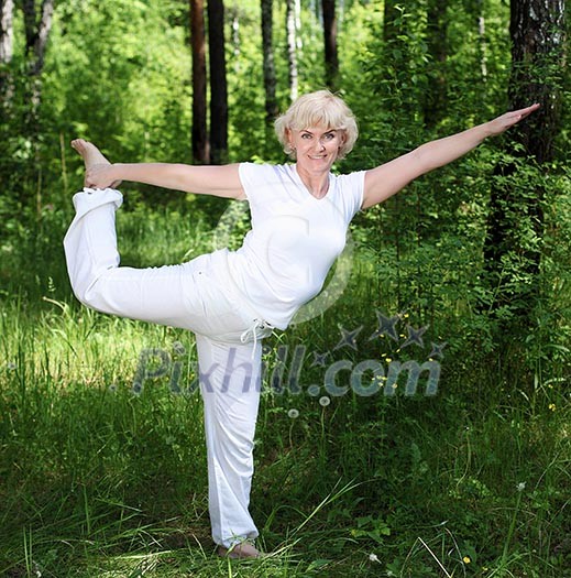 An elderly woman practices yoga in nature. The symbol of healthy lifestyle An elderly woman practices yoga in nature. The symbol of healthy lifestyle