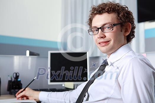 a young smiling businessman in formal wear in office a young smiling businessman in formal wear in office