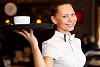 Portrait of young waitress in white blouse holding a tray