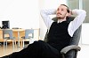 A business man in his office rests in the chair.