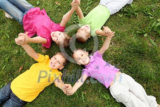 Group of children lying on the grass in the summer park Group of children lying on the grass in the summer park