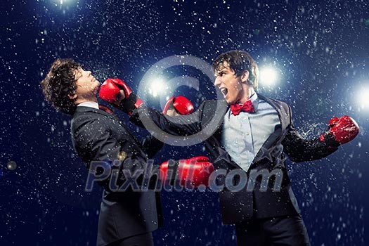 Two young businessman boxing againts dark background . conceptual collage Two young businessman boxing againts dark background . conceptual collage