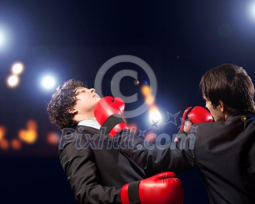 Two young businessman boxing againts dark background . conceptual collage Two young businessman boxing againts dark background . conceptual collage