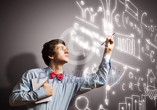 Image of thoughtful male student holding notebook in classroom Image of thoughtful male student holding notebook in classroom
