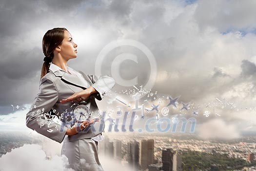 Image of young businesswoman holding alarmclock against illustration Image of young businesswoman holding alarmclock against illustration