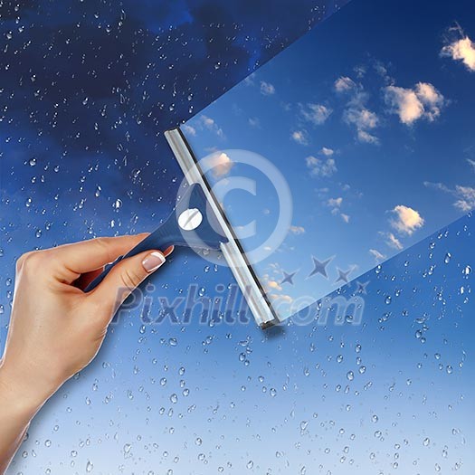 Hand cleaning window with blue sky and white clouds Hand cleaning window with blue sky and white clouds