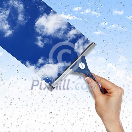 Hand cleaning window with blue sky and white clouds Hand cleaning window with blue sky and white clouds