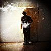 Image of young businessman standing with back opening door