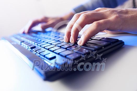 Click! Hands of a man on a keyboard with blue backlighting. Click! Hands of a man on a keyboard with blue backlighting.