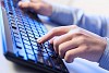 Click! Hands of a man on a keyboard with blue backlighting.