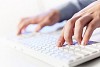 Click! Hands of a man on a keyboard with blue backlighting.