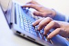 Click! Hands of a man on a keyboard with blue backlighting.