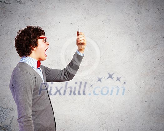 Young businessman with a red tie shouting furiously at his mobile phone Young businessman with a red tie shouting furiously at his mobile phone