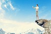 Image of businesswoman in blindfold standing on edge of mountain