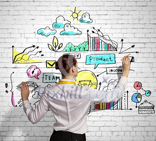 Businesswoman standing with back drawing business ideas on wall Businesswoman standing with back drawing business ideas on wall