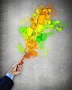 Close-up of human hand holding paint brush making colorful paint splashes