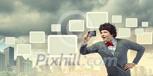 Image of young man in red tie with photo camera taking pictures