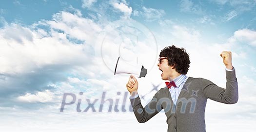Portrait of young man shouting loudly using megaphone Portrait of young man shouting loudly using megaphone