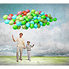 Image of father and son holding bunch of colorful balloons