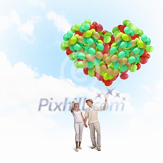 Image of young couple holding bunch of colorful balloons Image of young couple holding bunch of colorful balloons