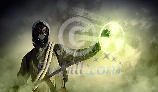 Image of man in gas mask and protective uniform touching radioactivity sign Image of man in gas mask and protective uniform touching radioactivity sign