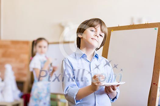 Image of little cute boy painting pictures at kindergarten Image of little cute boy painting pictures at kindergarten