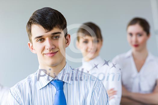 Smiling successful businessman with colleagues at background Smiling successful businessman with colleagues at background