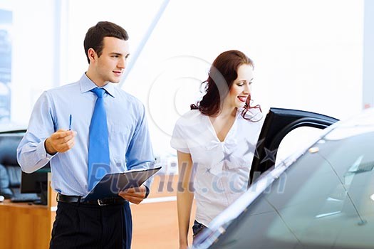 Attractive woman at car salon with consultant choosing a car Attractive woman at car salon with consultant choosing a car