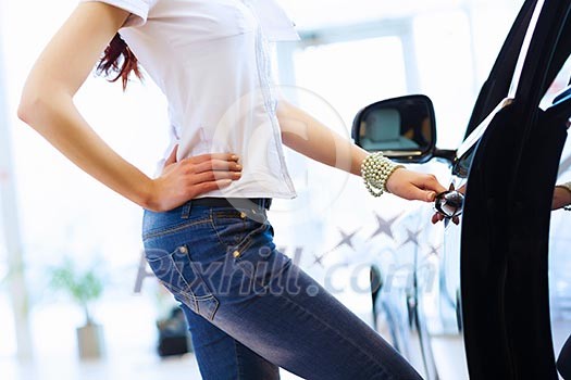 Pretty woman standing near car at car center. Choosing a car Pretty woman standing near car at car center. Choosing a car