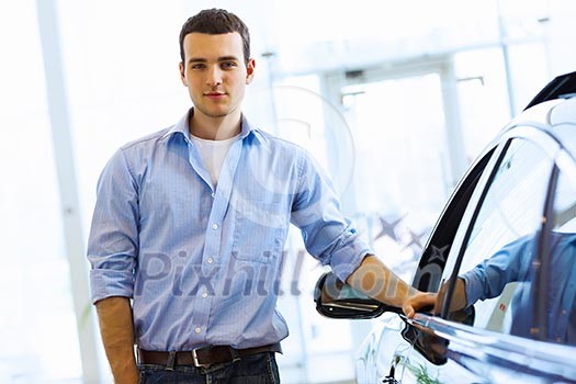 Handsome young man consultant at car salon standing near car Handsome young man consultant at car salon standing near car