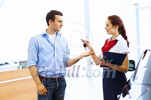 Young man choosing car at salon with help of consultant Young man choosing car at salon with help of consultant