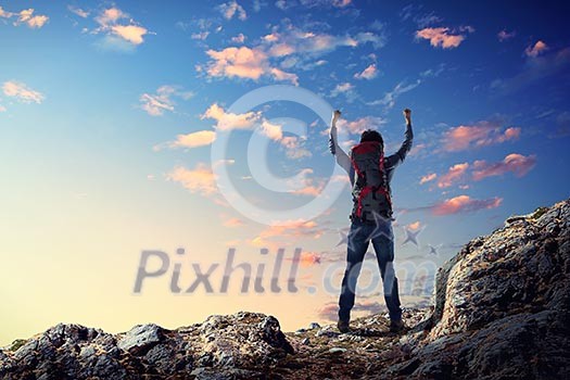 Image of young man mountaineer standing atop of rock