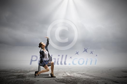 Image of businesswoman sitting on chair under sun lights Image of businesswoman sitting on chair under sun lights