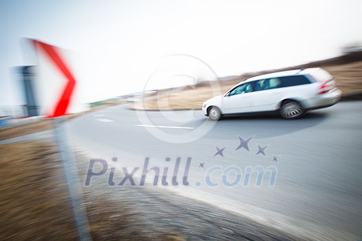 Traffic concept: car driving fast through a sharp turn (motion blur is used to convey movement) Traffic concept: car driving fast through a sharp turn (motion blur is used to convey movement)