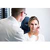 Optometry concept - pretty young woman having her eyes examined by an eye doctor (shallow DOF; color toned image)