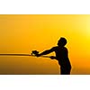 Fisherman silhouette on the beach at colorful sunset