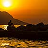 Fisherman silhouette on the beach at colorful sunset